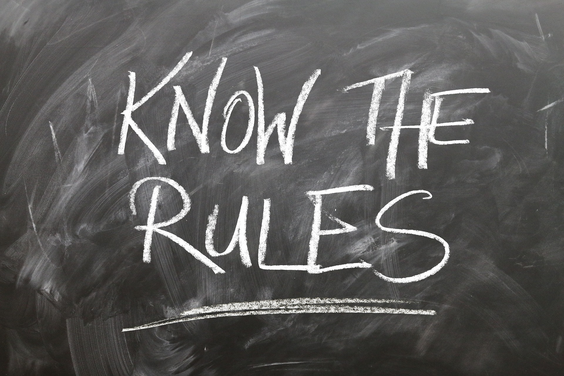 Business lawyer writes Know the Rules on a chalkboard